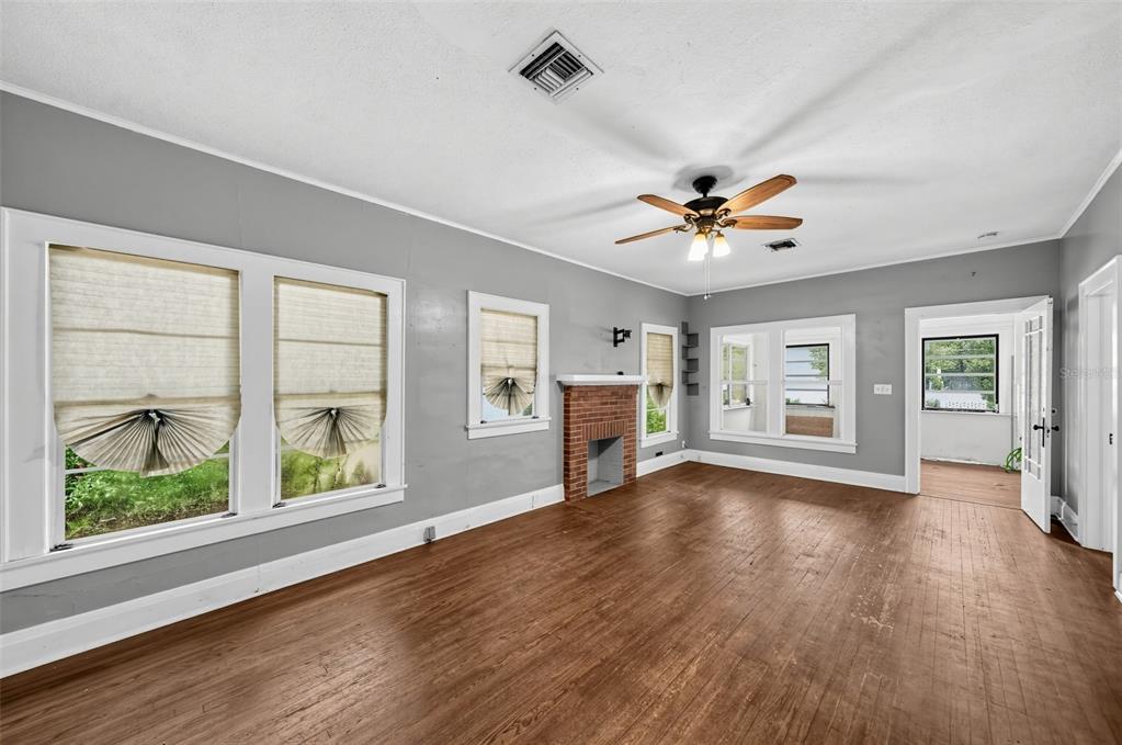 A living room features gray walls, hardwood floors, a brick fireplace, and a ceiling fan — 1203 KING AVENUE, LAKELAND, FL