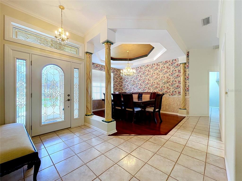 A tiled foyer leads to a dining area with floral wallpaper, columns, and a tray ceiling — 1826 WESTMINSTER COURT, LAKELAND, FL