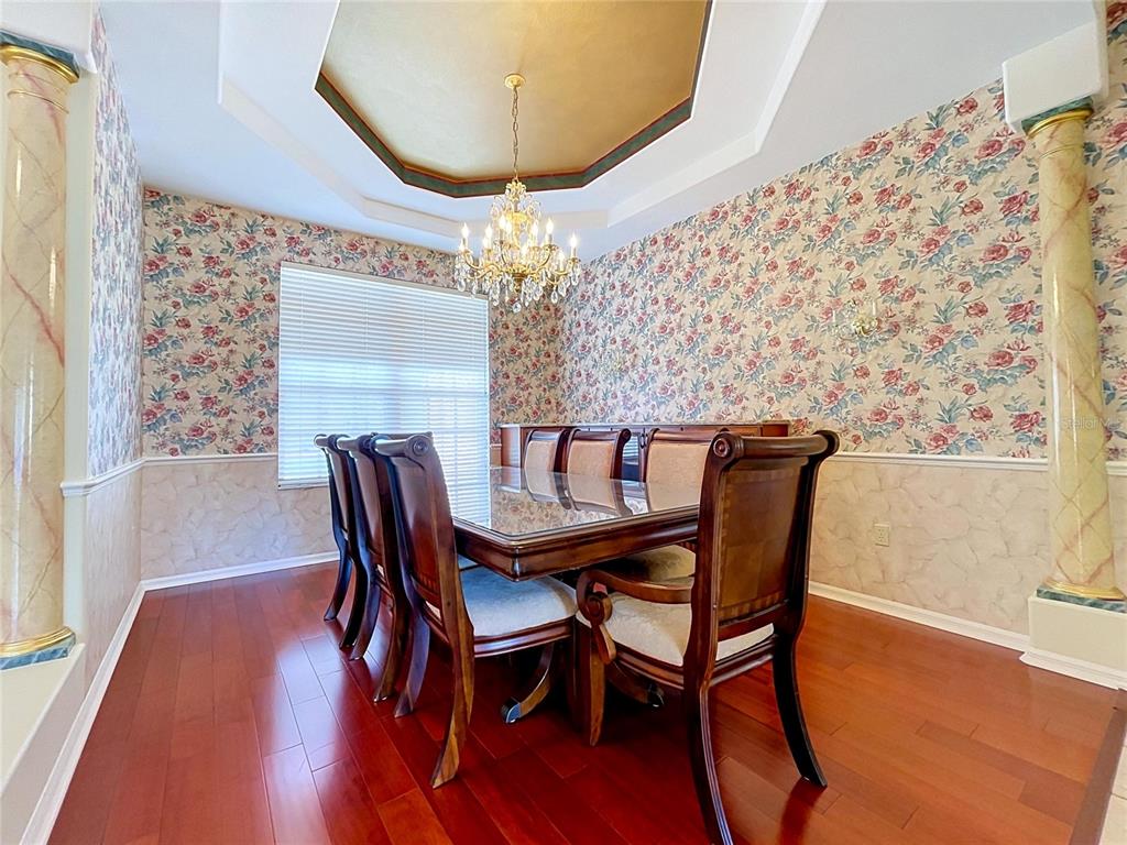 A dining room features floral wallpaper, a gold tray ceiling, and a wooden table set — 1826 WESTMINSTER COURT, LAKELAND, FL