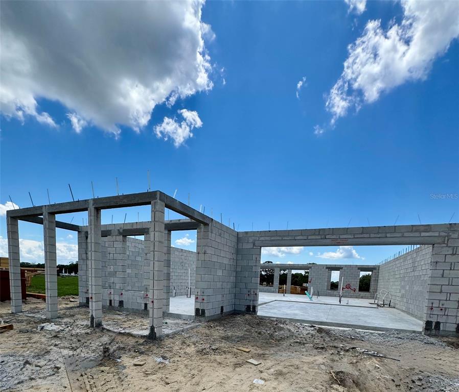 The exterior of a house under construction features concrete block walls and open framing — 30237 RUSTIC MILL STREET, MOUNT DORA, FL