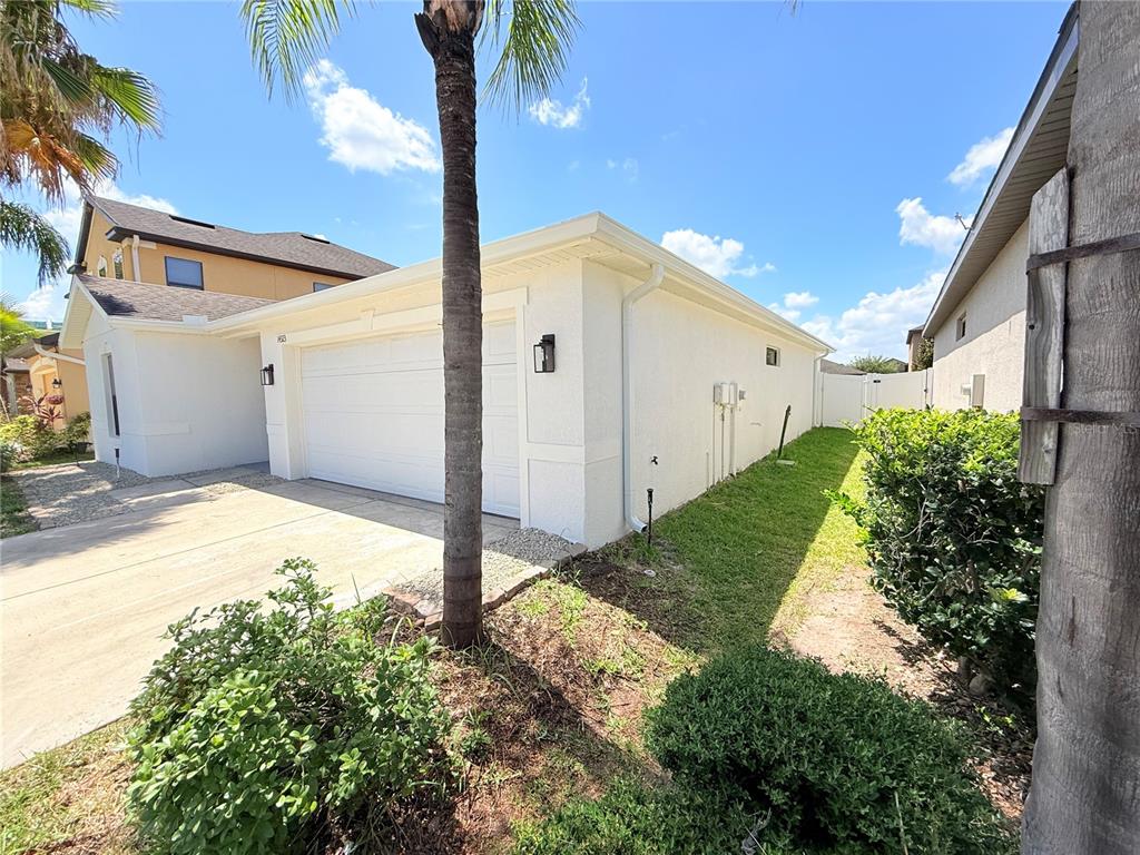 The exterior of a white house features a two-car garage and a side yard — 14323 HADDON MIST DRIVE, WIMAUMA, FL
