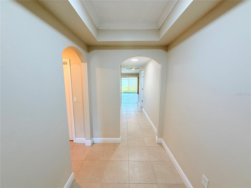 A tiled hallway features arched entryways and a tray ceiling leading to a bright room — 14323 HADDON MIST DRIVE, WIMAUMA, FL