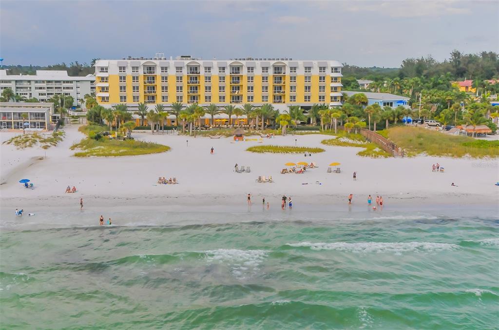 An aerial view of a multi-story yellow hotel building situated directly on a sandy beach — 915 SEASIDE DRIVE UNIT 402, Weeks 10-13, SARASOTA, FL
