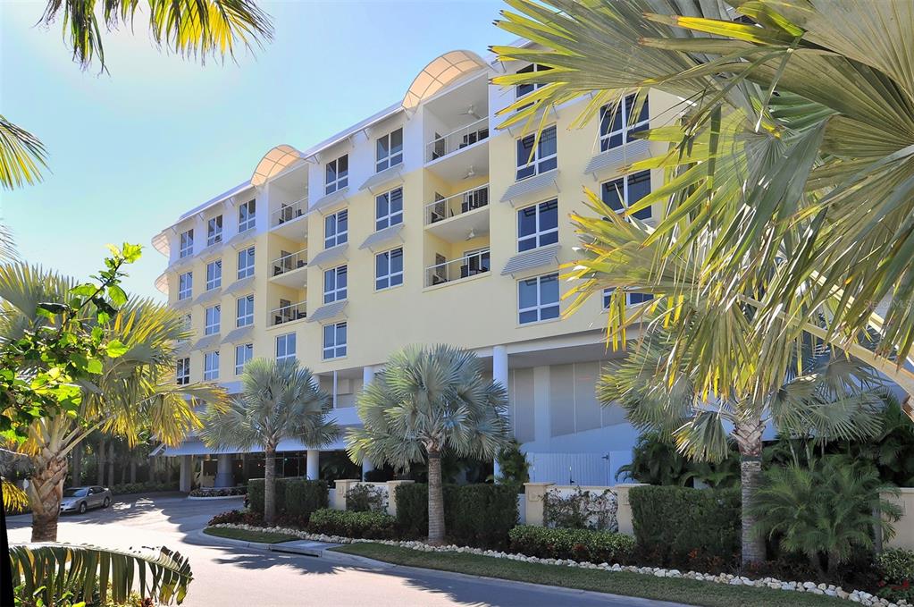 A multi-story yellow apartment building with balconies is surrounded by palm trees and landscaping — 915 SEASIDE DRIVE UNIT 402, Weeks 10-13, SARASOTA, FL