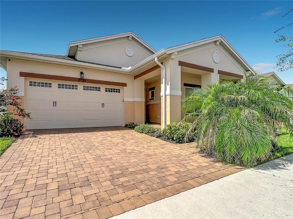 A single-story house with a paved driveway, two-car garage, and a large palm tree — 2720 GREENLANDS STREET, ST CLOUD, FL