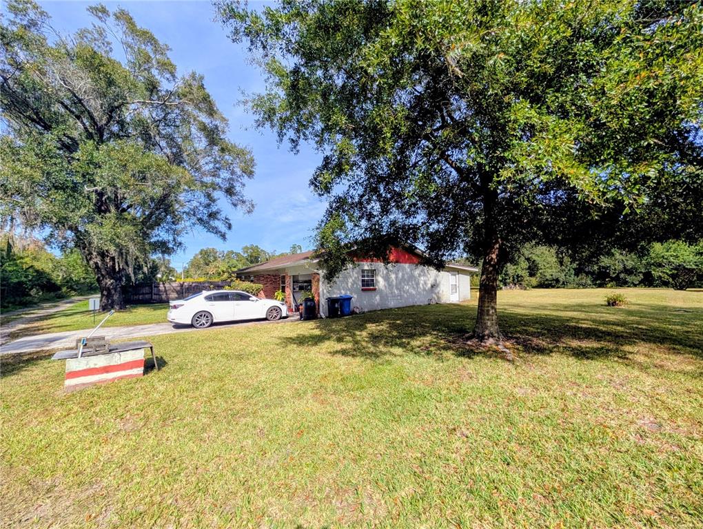 A white sedan is parked on a driveway next to a house with red trim — 8410 PETERSON ROAD, ODESSA, FL