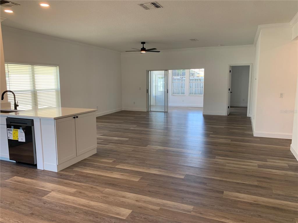 An open-concept living area features light wood-look flooring, white walls, and a kitchen island — 133 JAYBEE AVENUE, DAVENPORT, FL