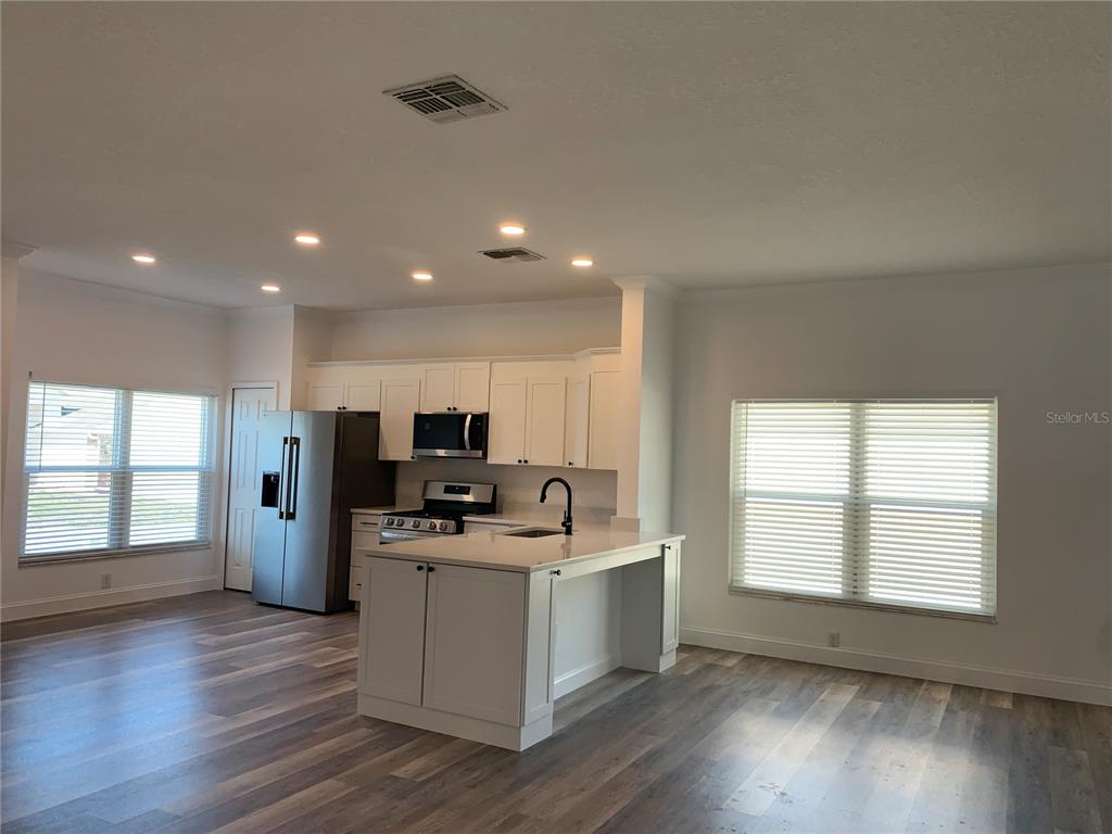 A kitchen with white cabinetry, stainless steel appliances, and a central island with wood flooring — 133 JAYBEE AVENUE, DAVENPORT, FL