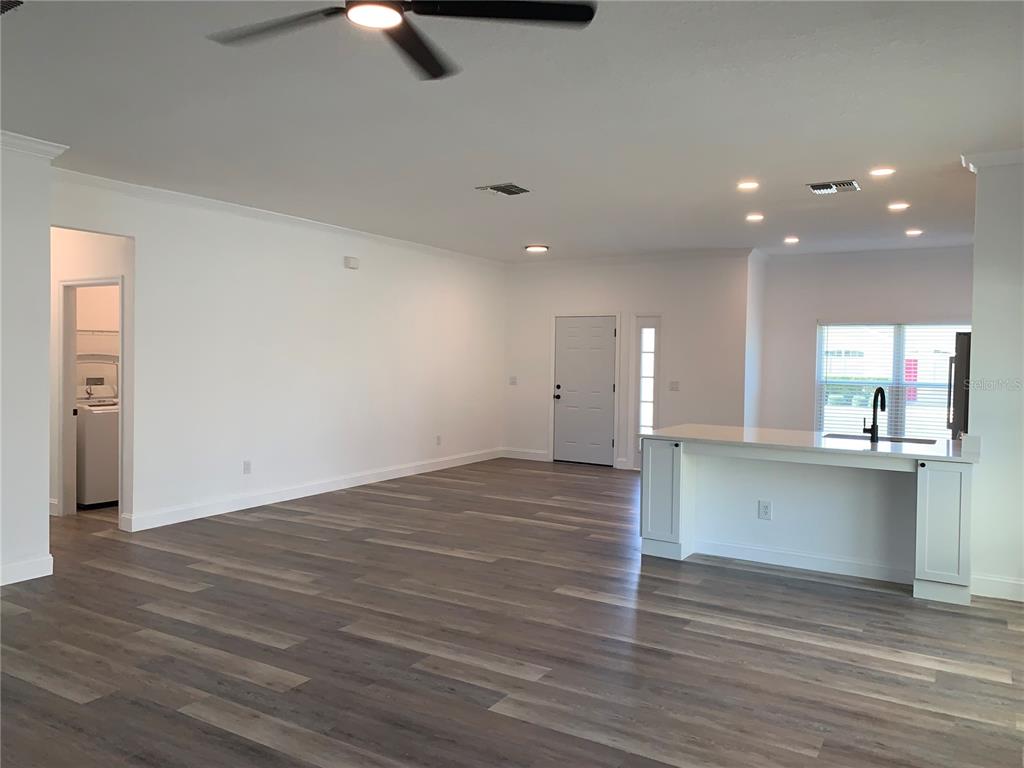 An open-concept living area features wood-look flooring, a white kitchen island, and a ceiling fan — 133 JAYBEE AVENUE, DAVENPORT, FL