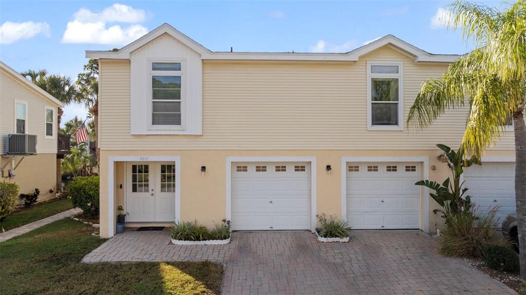 A two-story yellow townhouse with a double garage and a paved driveway — 7641 SAILWINDS PASS, PORT RICHEY, FL