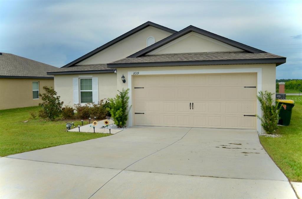 A single-story house with a beige exterior, a two-car garage, and a concrete driveway — 1639 SWAN LAKE CIRCLE, DUNDEE, FL