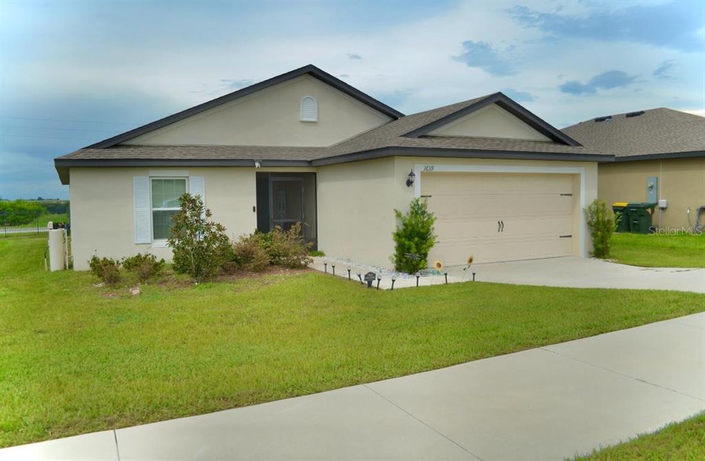 A single-story house with a beige stucco exterior, a two-car garage, and a front lawn — 1639 SWAN LAKE CIRCLE, DUNDEE, FL