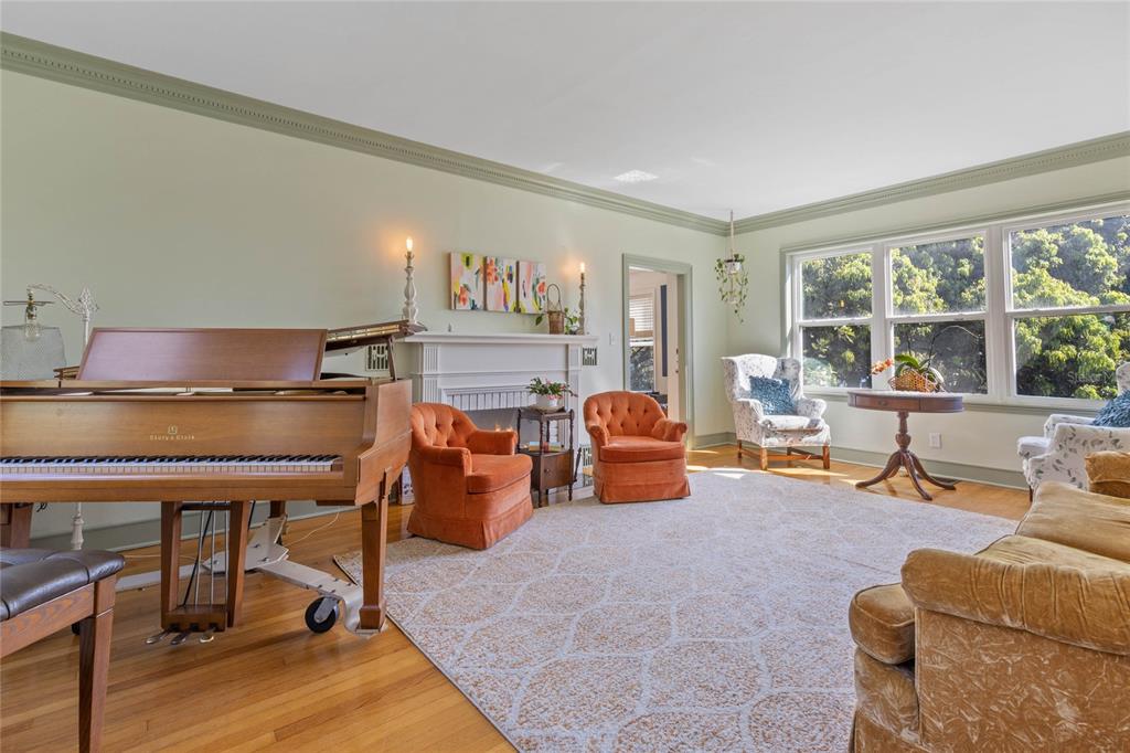 A living room features a grand piano, a fireplace, orange armchairs, and large windows — 694 LAKE OTIS DRIVE SE, WINTER HAVEN, FL