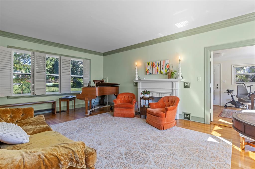 A living room features a grand piano, orange armchairs, a gold sofa, and a fireplace — 694 LAKE OTIS DRIVE SE, WINTER HAVEN, FL