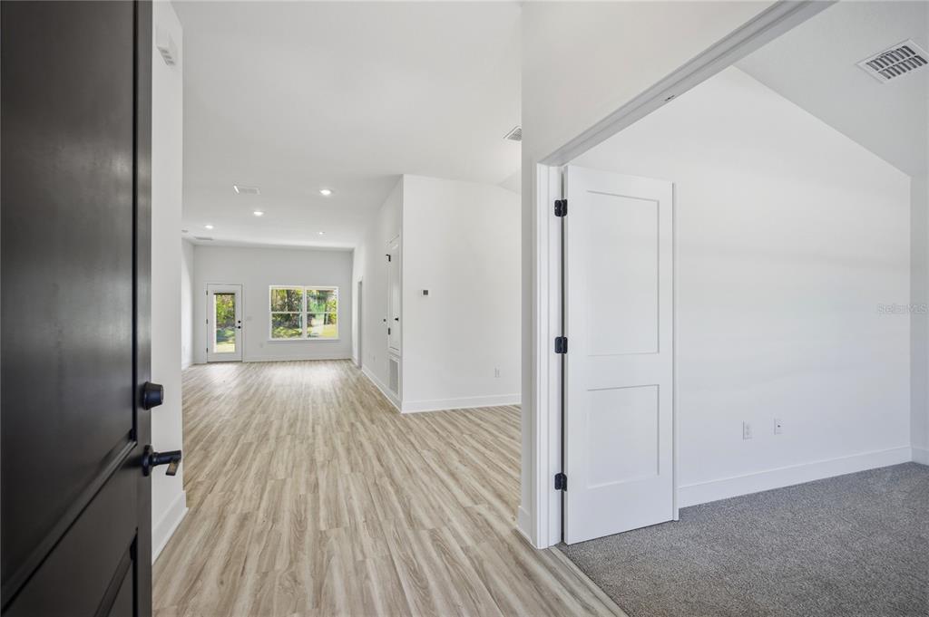 An interior view showing a room with carpet, a hallway with wood-look flooring, and doors — 13855 NW 150TH CIRCLE, ALACHUA, FL