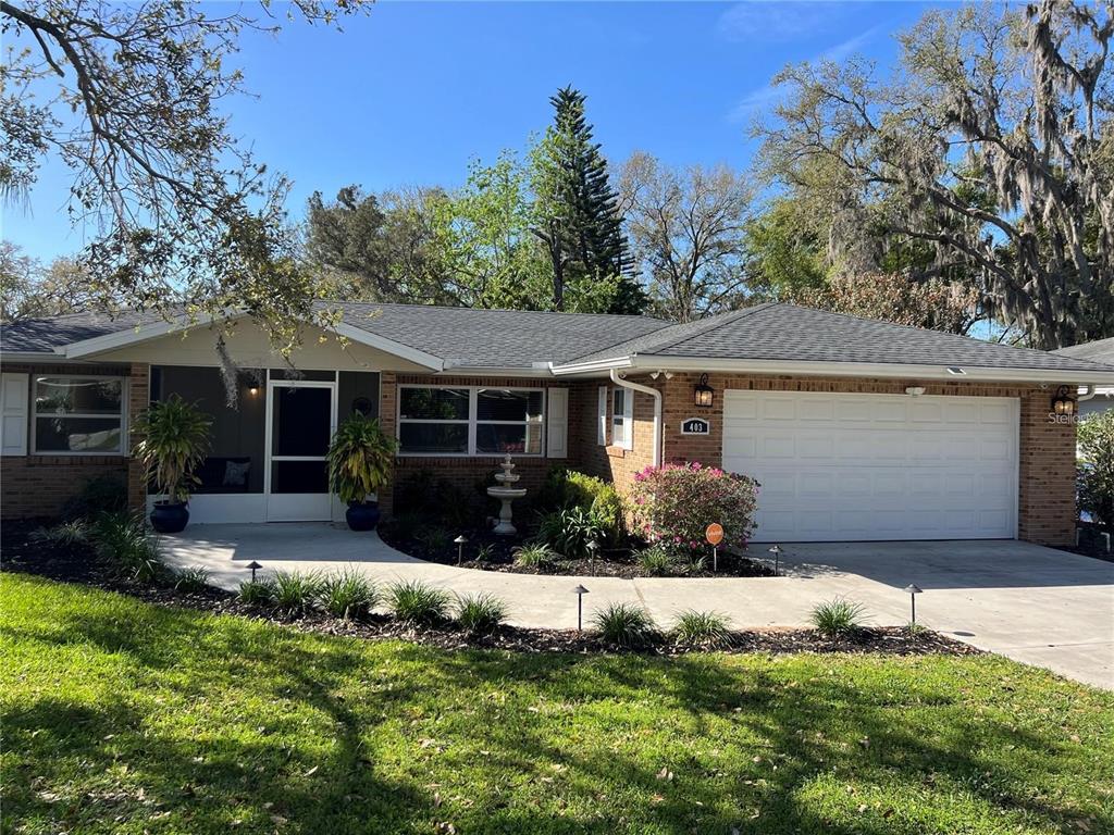A single-story brick house with a white garage door, screened porch, and landscaped front yard — 403 VIRGINIA STREET, MINNEOLA, FL