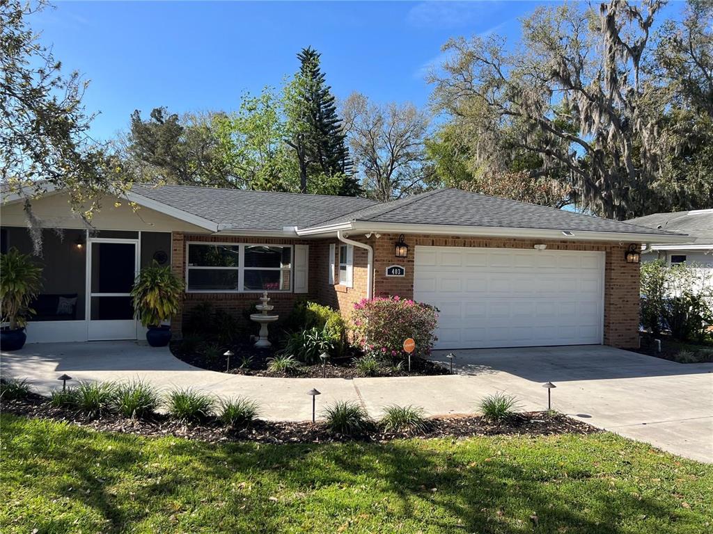 A single-story brick house with a white garage door and a screened-in front porch — 403 VIRGINIA STREET, MINNEOLA, FL