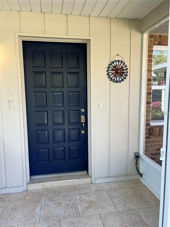 A dark blue front door with a decorative metal flower wall hanging on a porch — 403 VIRGINIA STREET, MINNEOLA, FL