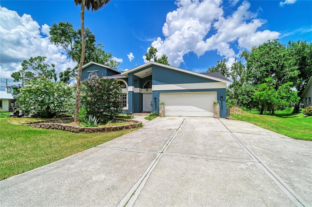 A blue single-story house features a two-car garage, a concrete driveway, and a landscaped yard — 6519 28TH AVENUE E, BRADENTON, FL