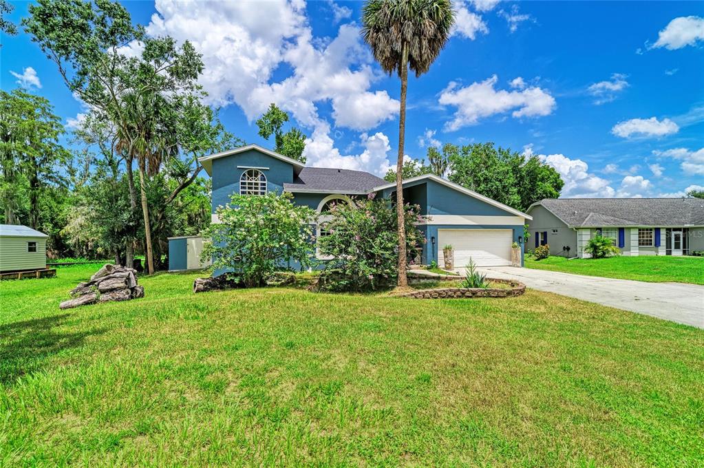 A blue two-story house with a garage and a palm tree in the front yard — 6519 28TH AVENUE E, BRADENTON, FL