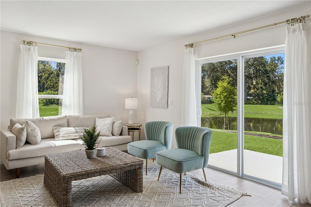 A living room features a beige sofa, two teal chairs, and a sliding glass door — 1665 GREAT OSPREY WAY, NEW SMYRNA BEACH, FL