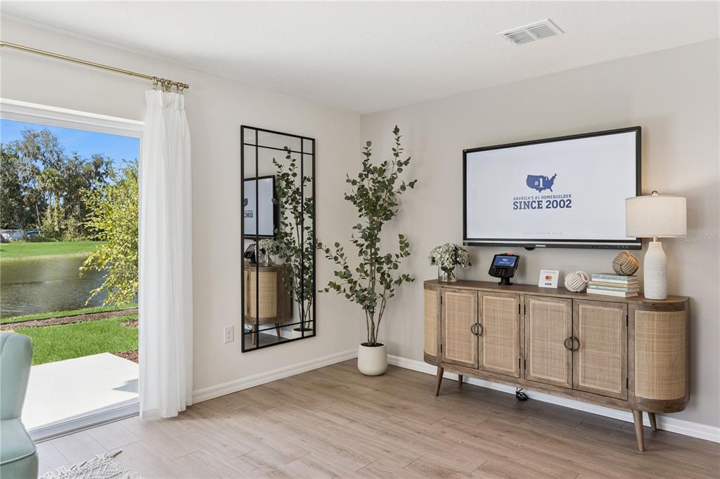 A living room features a wall-mounted television, a wooden console, a mirror, and a sliding door — 1665 GREAT OSPREY WAY, NEW SMYRNA BEACH, FL
