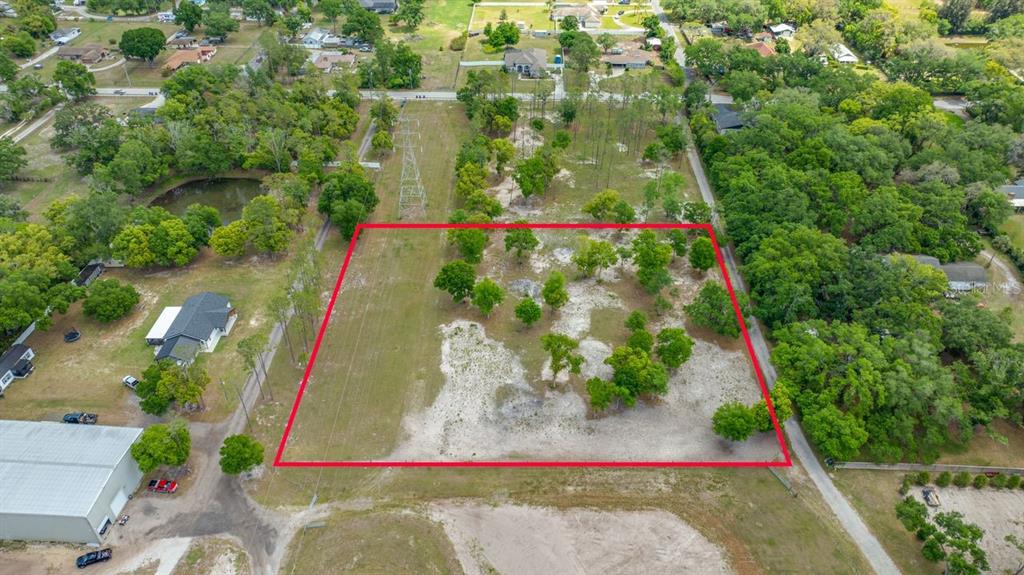An aerial view shows a rectangular, partially wooded vacant lot outlined in red — 00 HANNA ROAD, LUTZ, FL