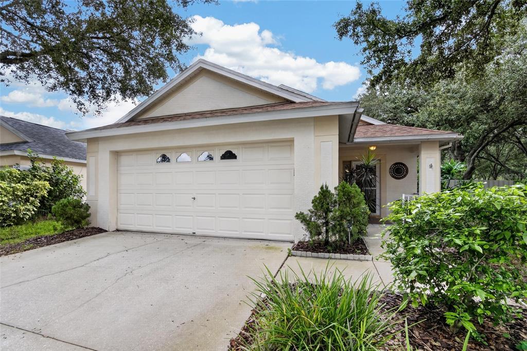 A single-story house with a beige stucco exterior, a two-car garage, and a front porch — 5848 MEADOWPARK PLACE, LITHIA, FL