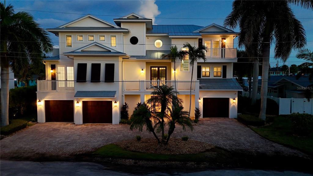 A three-story coastal home with a metal roof, multiple balconies, and a paved driveway — 529 77TH STREET, HOLMES BEACH, FL
