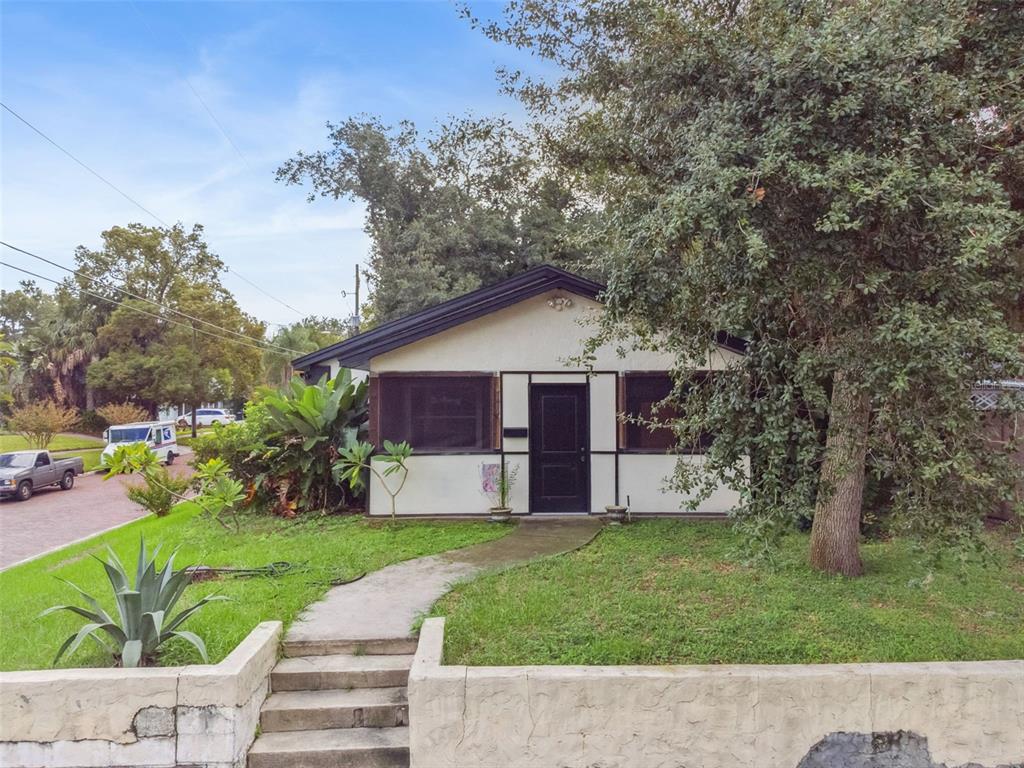 A single-story house with a black door and trim sits behind a low concrete wall — 1417 BELGRADE AVENUE, ORLANDO, FL