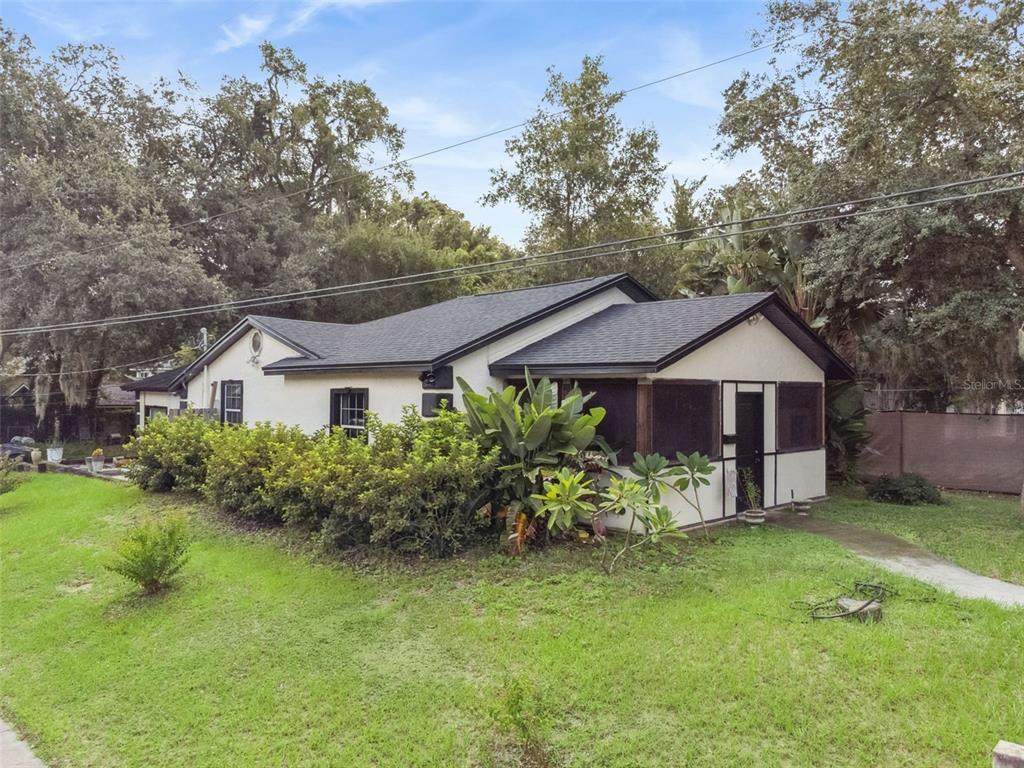 A single-story house with a white stucco exterior, dark trim, and a screened-in porch — 1417 BELGRADE AVENUE, ORLANDO, FL