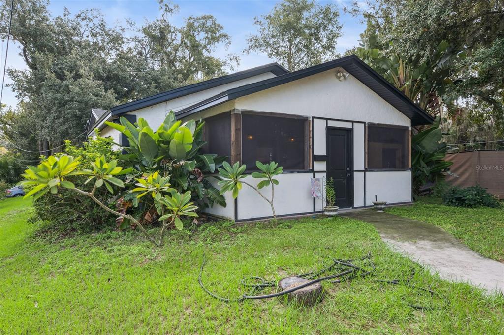 A white house with black trim and a screened-in porch sits on a grassy lot — 1417 BELGRADE AVENUE, ORLANDO, FL