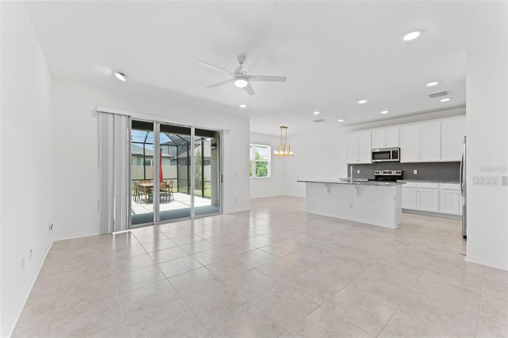 An open-concept kitchen and living area features white cabinetry, granite countertops, and tile flooring — 32034 SAPNA CHIME DRIVE, WESLEY CHAPEL, FL