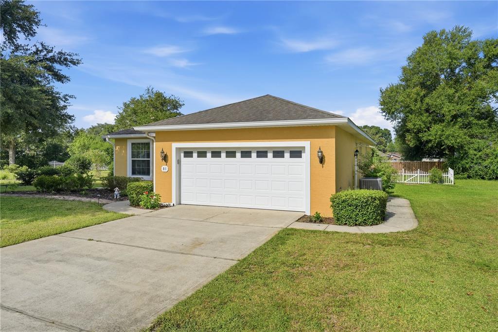 A yellow detached garage with a white door and a concrete driveway sits on grass — 81 TWIN LAKE CIR, UMATILLA, FL