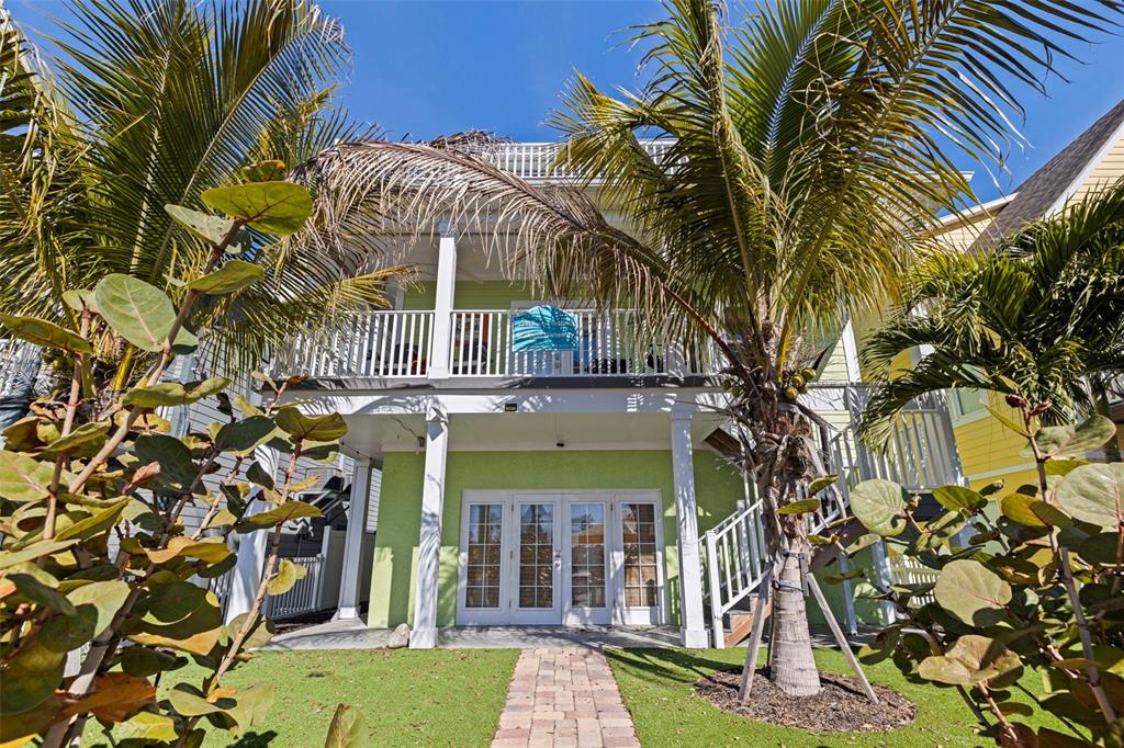 A two-story light green house features a balcony, French doors, and a brick walkway — 5429 ESSEX AVENUE S, GULFPORT, FL