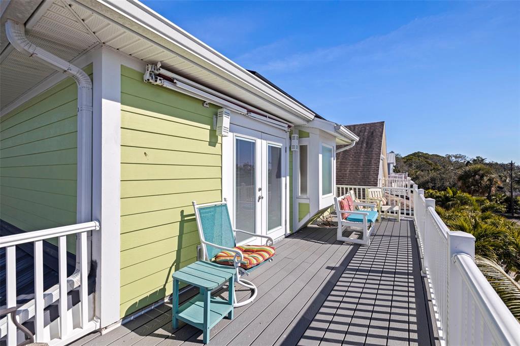 A light green house features a wooden deck with outdoor seating and white railings — 5429 ESSEX AVENUE S, GULFPORT, FL