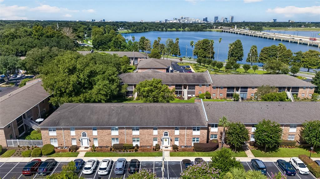 An aerial view shows multi-story brick apartment buildings with parking lots near a large lake — 4386 LAKE UNDERHILL ROAD UNIT D, ORLANDO, FL