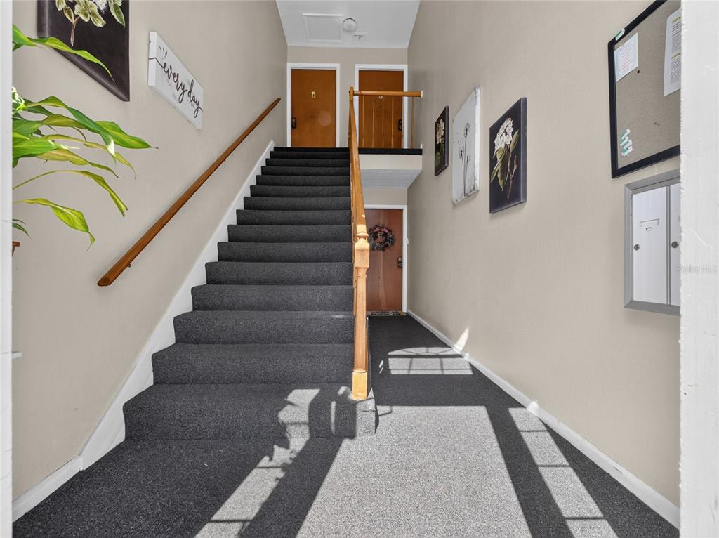 A carpeted staircase leads to an upper landing with two doors in a beige hallway — 4386 LAKE UNDERHILL ROAD UNIT D, ORLANDO, FL