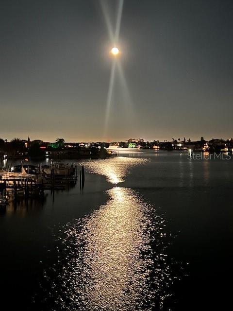 A full moon shines over a dark waterway with boat docks and distant coastal homes — 6061 2ND STREET E UNIT 55, ST PETE BEACH, FL