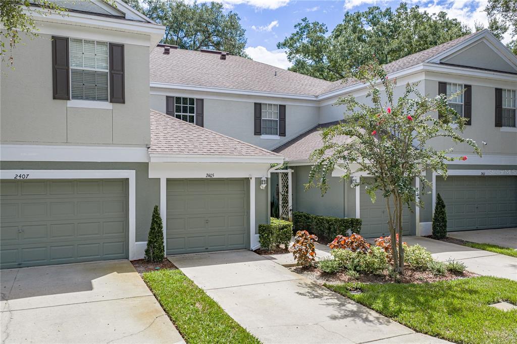 A multi-unit residential building with light green stucco siding, gray garage doors, and concrete driveways — 2405 EARLSWOOD COURT, BRANDON, FL