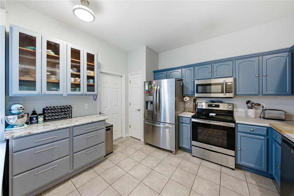 A kitchen features blue cabinets, stainless steel appliances, and light-colored granite countertops — 2405 EARLSWOOD COURT, BRANDON, FL