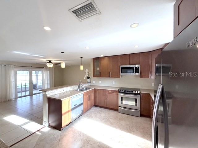 A kitchen with wood cabinets, stainless steel appliances, and tile floors overlooks an adjacent room — 2410 SHERBROOKE ROAD, WINTER PARK, FL