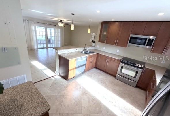 A kitchen with brown cabinets, granite countertops, and stainless steel appliances overlooks a living area — 2410 SHERBROOKE ROAD, WINTER PARK, FL