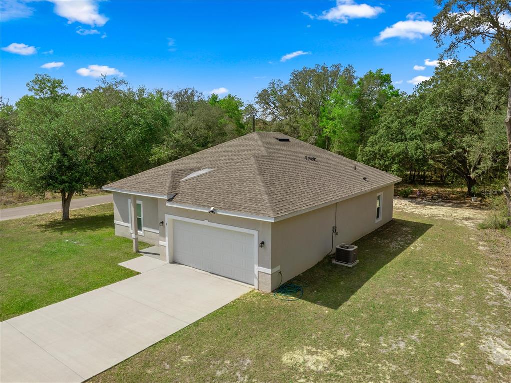 An aerial view of a single-story house with a tan exterior, shingled roof, and driveway — 2 MAGNOLIA PASS TRACE, OCKLAWAHA, FL