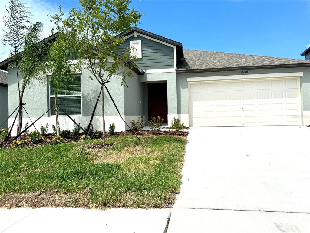 A single-story house with a light-colored stucco exterior, a two-car garage, and a front lawn — 11429 LINDEN DEPOT ROAD, SAN ANTONIO, FL