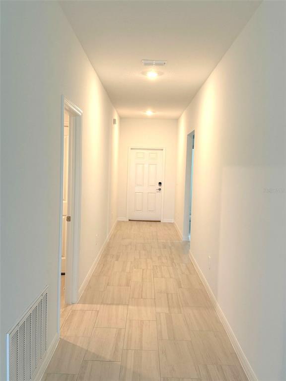 A hallway with light-colored tile flooring leads to a white door at the far end — 11429 LINDEN DEPOT ROAD, SAN ANTONIO, FL