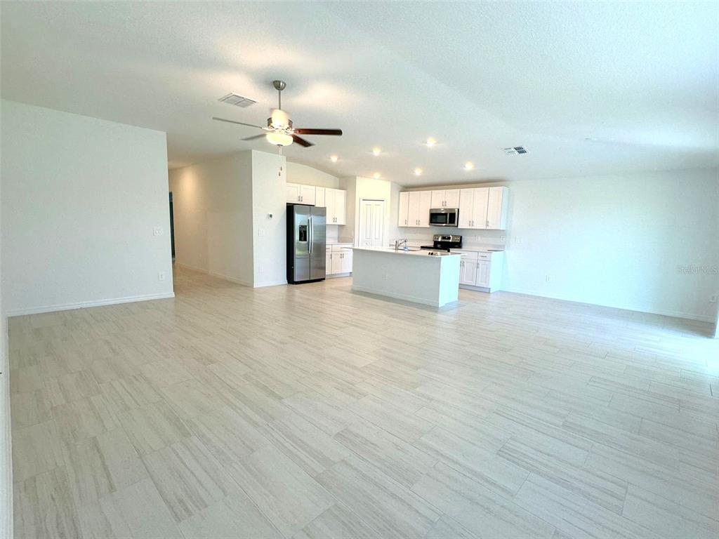 An open-concept kitchen and living area features white cabinetry, a center island, and light-colored flooring — 11429 LINDEN DEPOT ROAD, SAN ANTONIO, FL