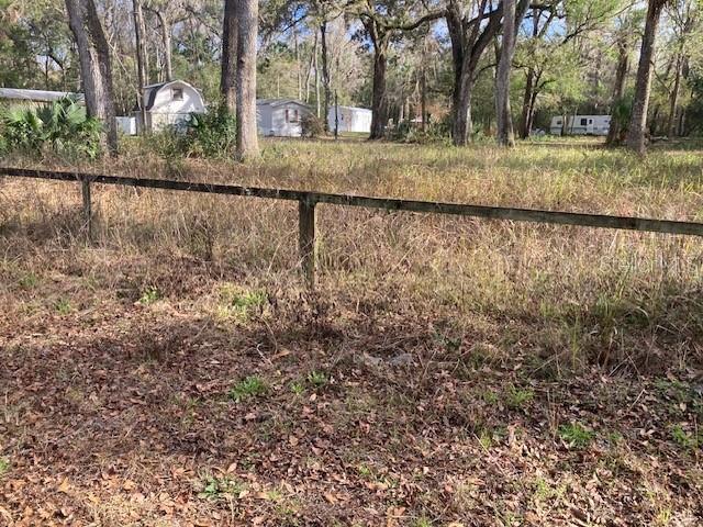 A wooden fence runs across a grassy lot with several small buildings in the background — 2456 N JUNGLE CAMP ROAD UNIT 1, INVERNESS, FL