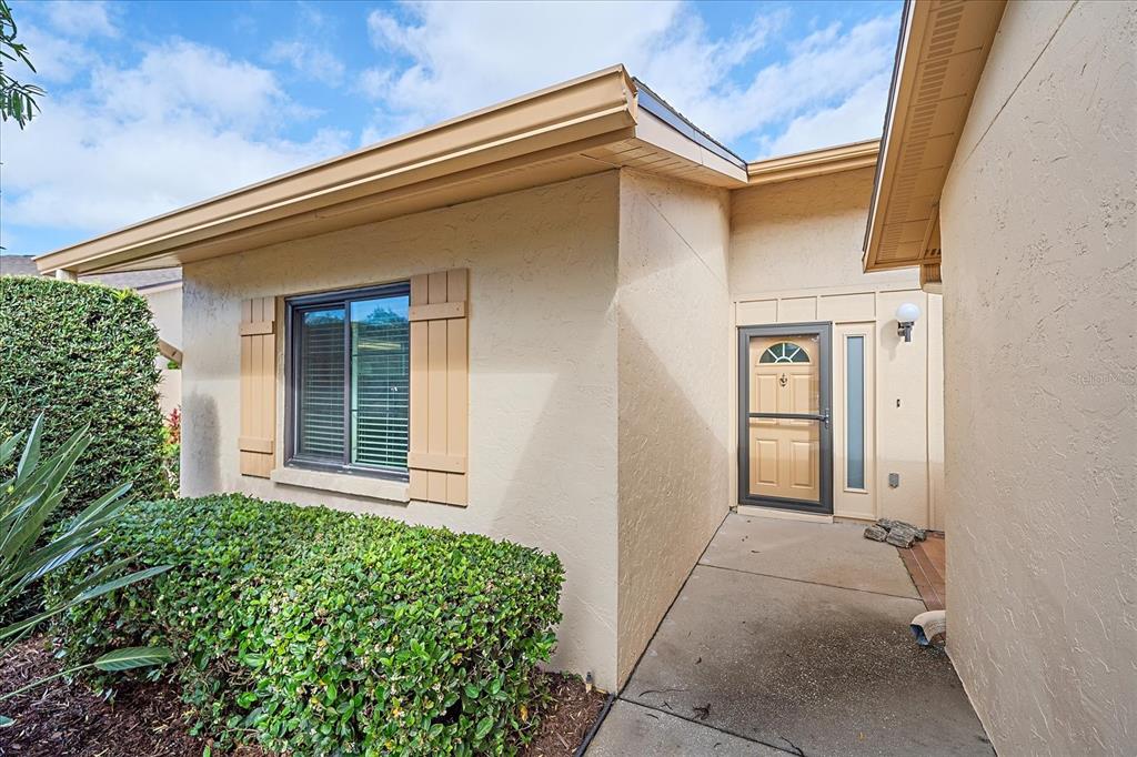 The exterior of a tan house features a front door with a storm door — 3135 GLEN ELYN BOULEVARD UNIT 13, SARASOTA, FL