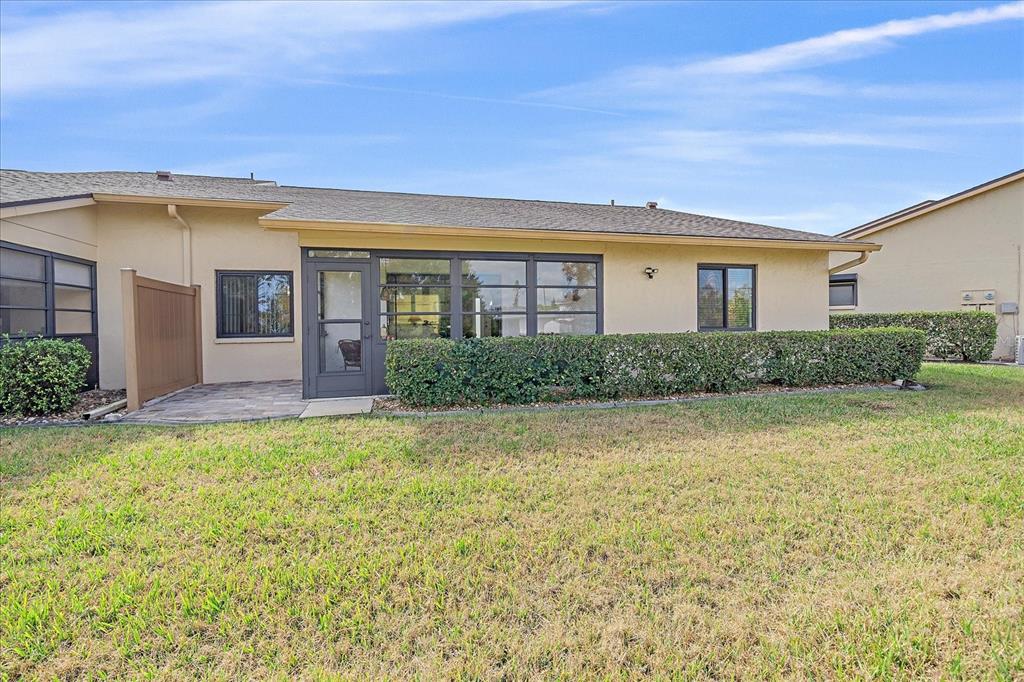The exterior of a single-story house features a screened-in porch, a small patio, and landscaping — 3135 GLEN ELYN BOULEVARD UNIT 13, SARASOTA, FL